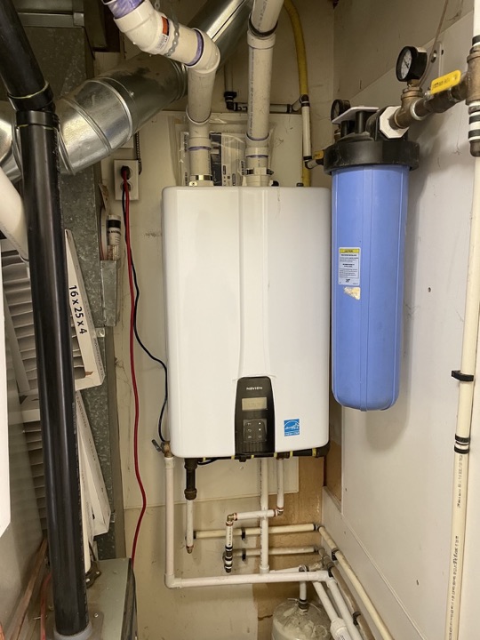 Wall-mounted Navien tankless water heater with venting and filtration