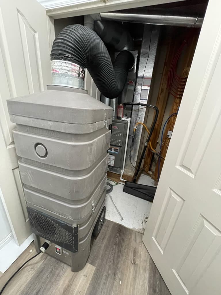 Professional negative-air duct cleaning equipment connected near a furnace