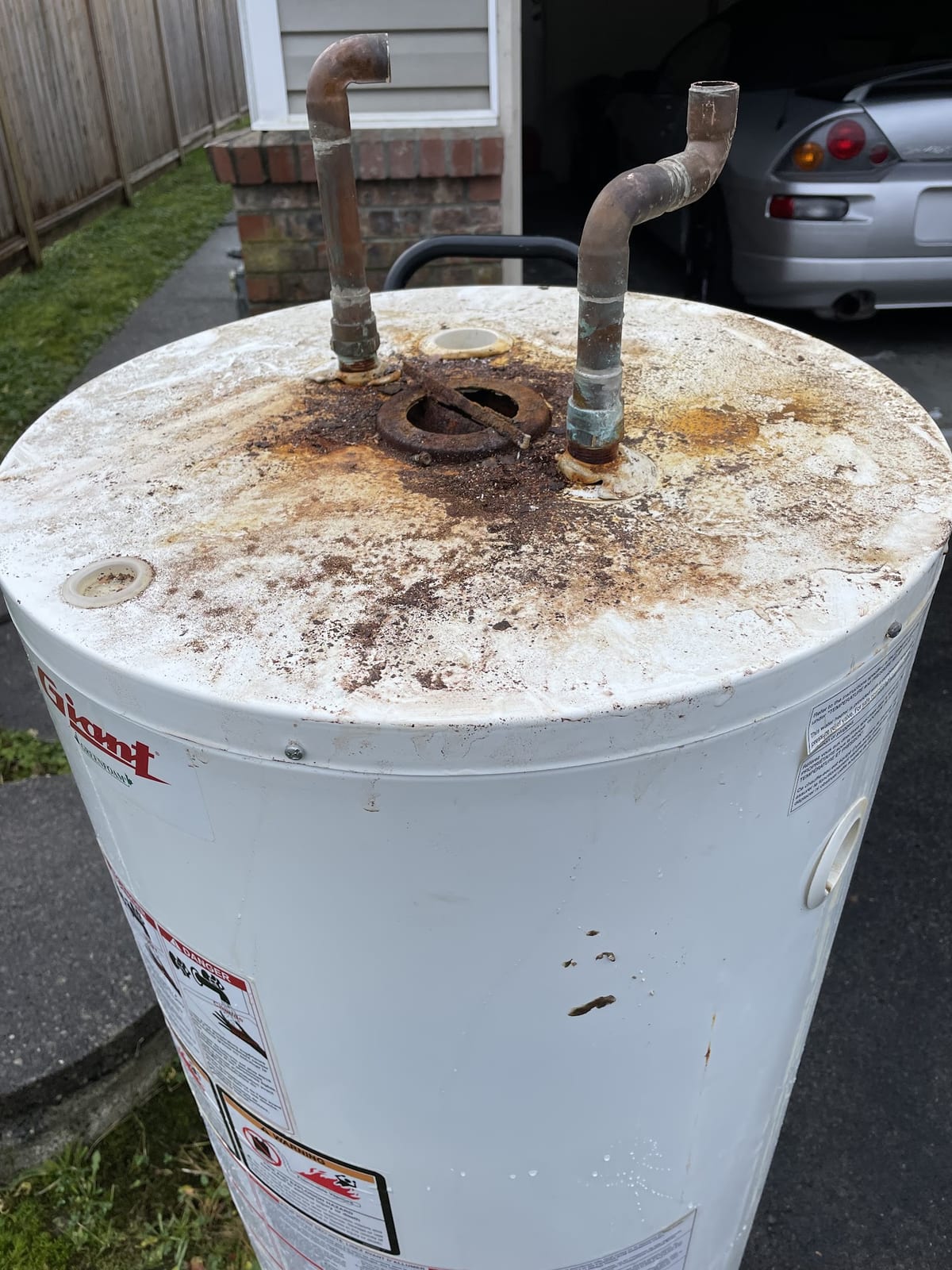 Removed Giant hot water tank outdoors with visible corrosion around the top